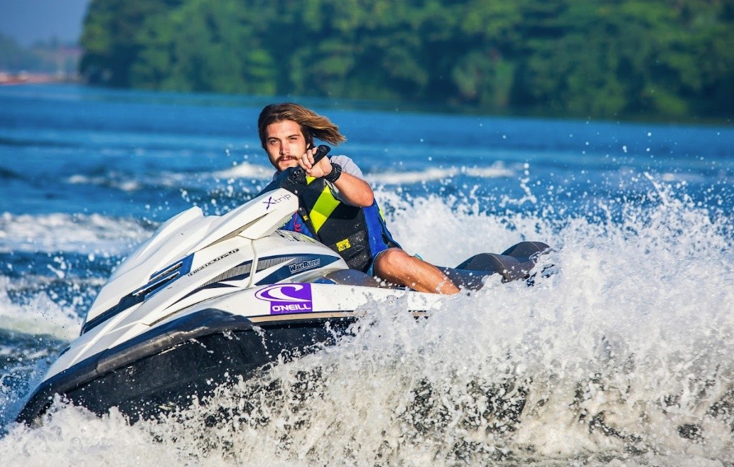 Person riding a jet ski on a lake with trees in the background.