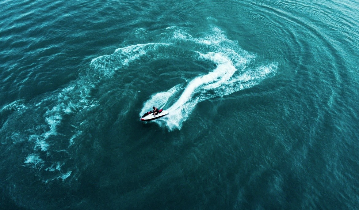 Aerial view of a jet ski making circular patterns in blue water.