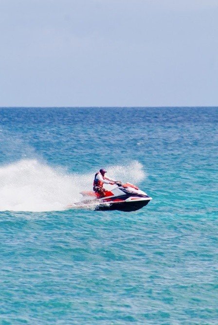 Person riding a jet ski on the ocean with a trail of water spray.
