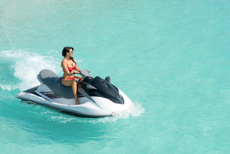 Person riding a jet ski on clear turquoise water.