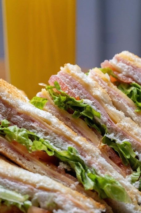 Close-up of a club sandwich with layers of turkey, lettuce, tomato, cheese, and bread.
