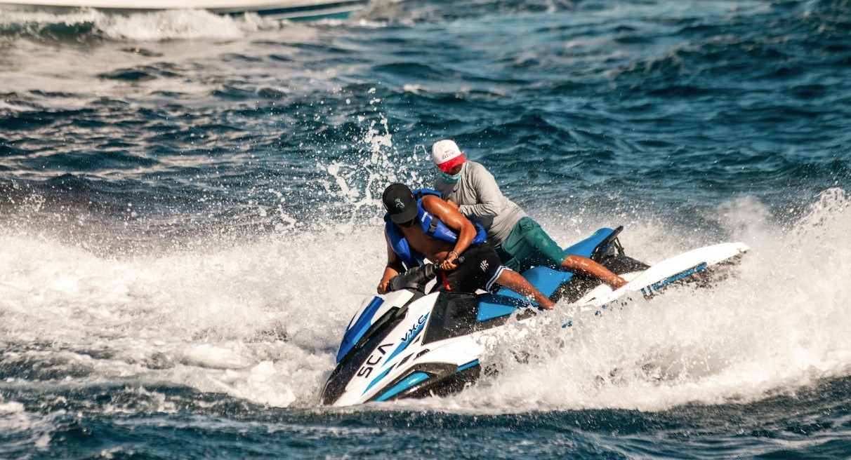 Two people riding a jet ski on choppy waters.