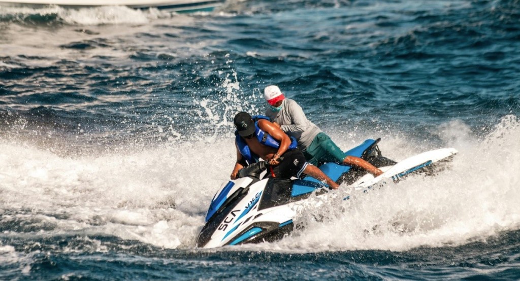 Two people riding a jet ski on choppy waters.