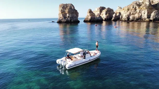 Boat with people near rocky cliffs in calm water.