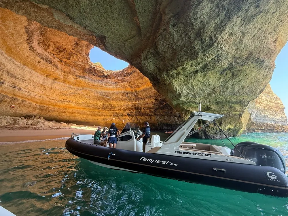 Boat with people in a cave with large rock formations and open sky above.