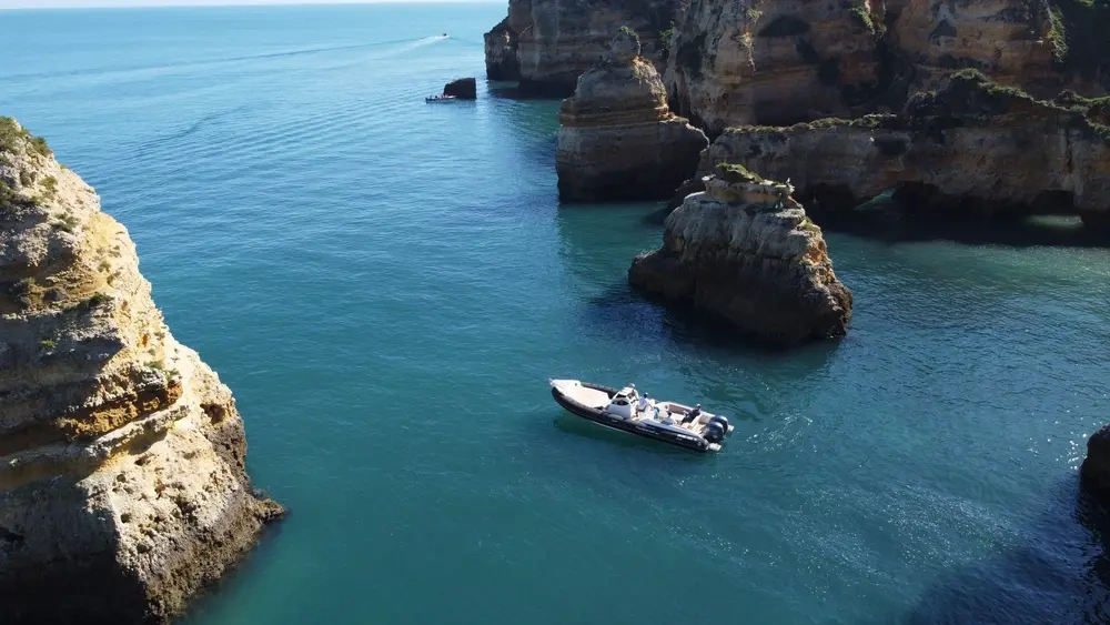 Boat on calm water near rocky cliffs and arches.
