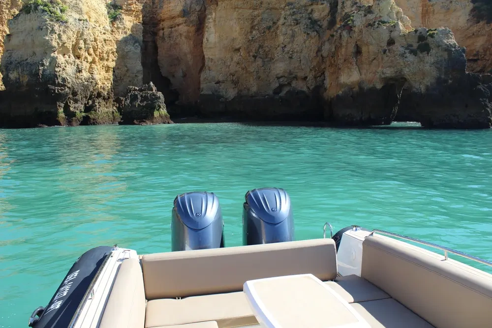 Boat facing rocky cliffs over turquoise water.
