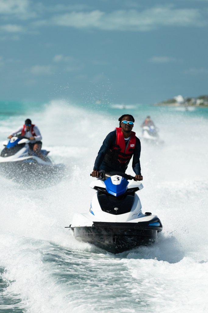 People riding jet skis on the ocean with splashing water.