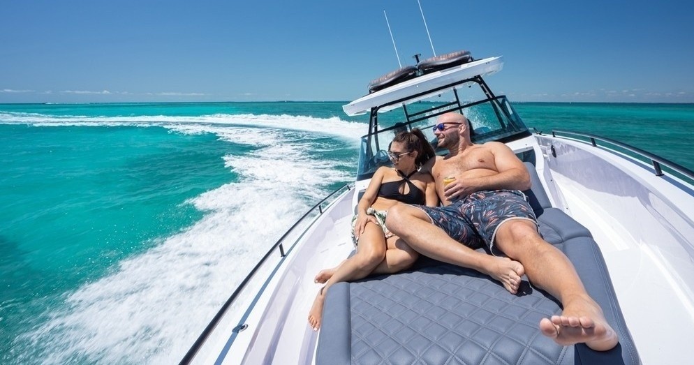 Couple relaxing on boat deck over turquoise sea under clear sky.