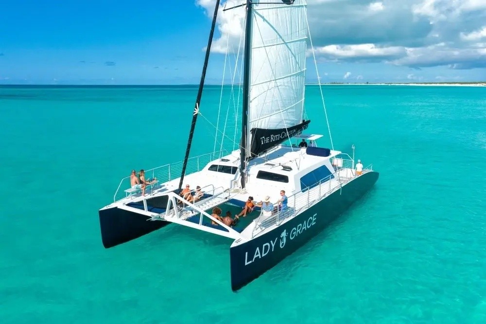 Catamaran 'Lady Grace' sailing on clear turquoise water with people on deck.