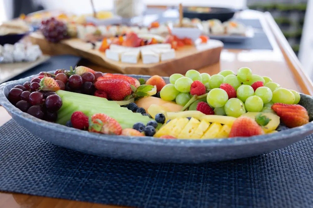 Plate with assorted fruits including grapes, strawberries, and melon slices on a table.
