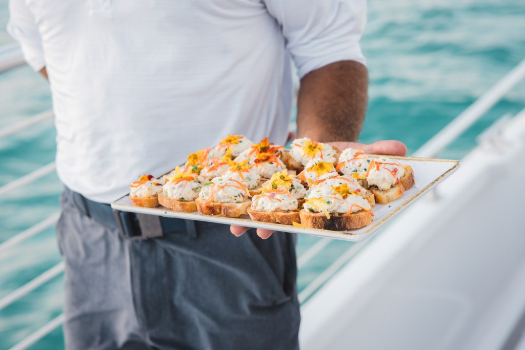 Person holds a tray of appetizers on a boat.