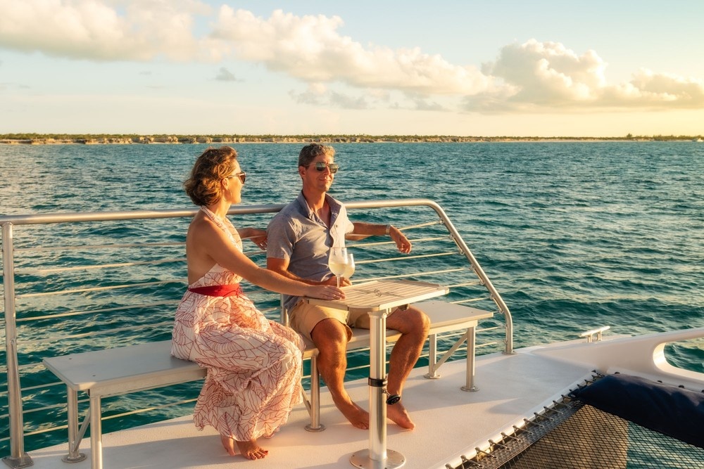 Couple enjoying drinks on a boat at sunset on the ocean.