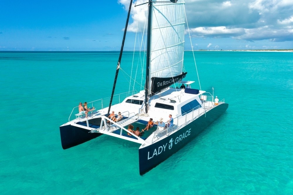 People relaxing on a sailboat named Lady Grace in turquoise waters under a blue sky.