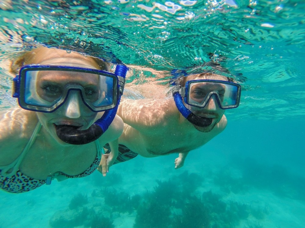 Two people snorkeling underwater in clear blue water.