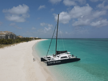 Catamaran on a clear beach with turquoise water and a cloudy sky.