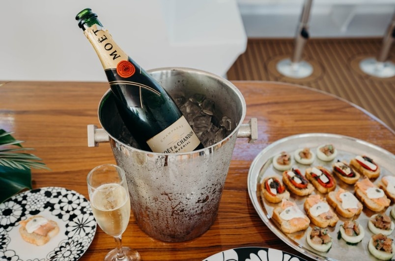 Champagne in ice bucket with appetizers on a wooden table.