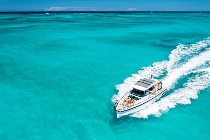 Boat speeding on clear turquoise ocean under blue sky.