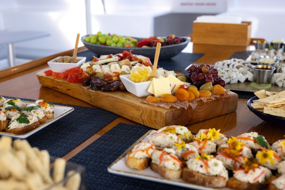 Assorted cheeses, fruits, and appetizers on wooden platters on a table.