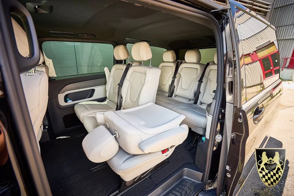 Spacious van interior with three rows of cream leather seats.