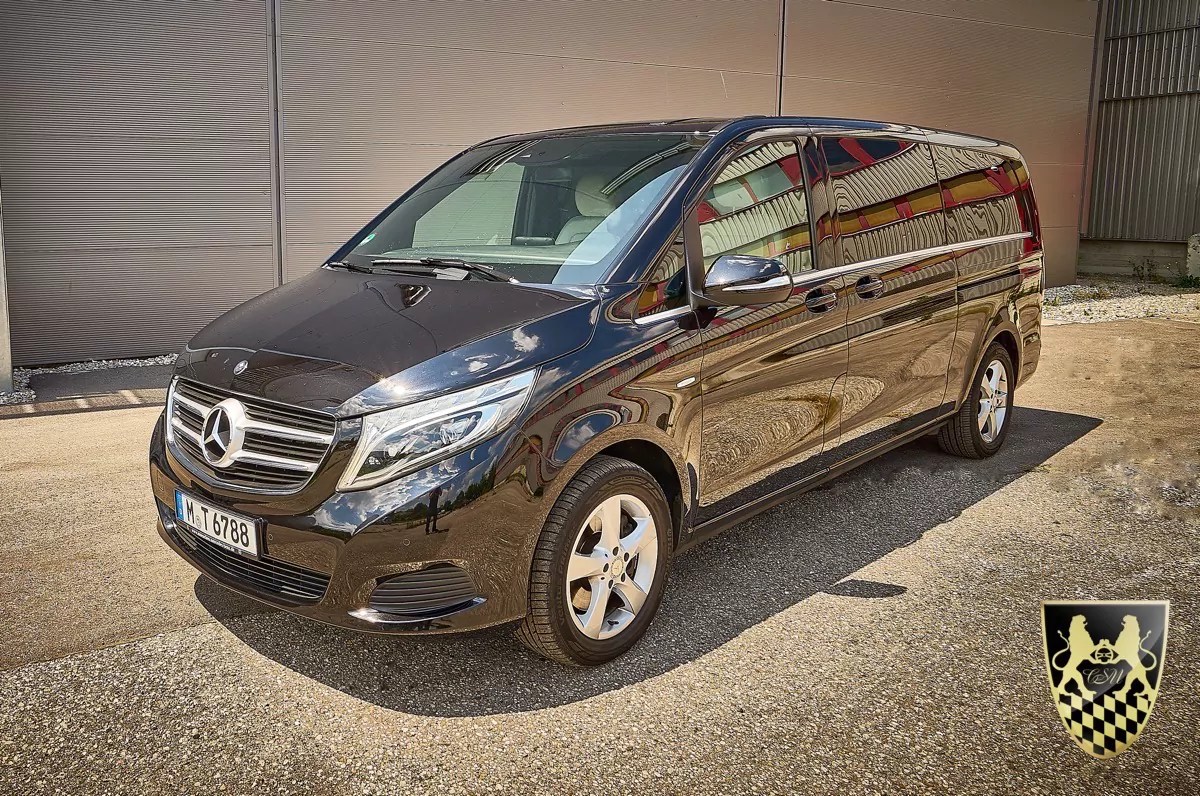 Black Mercedes-Benz van parked on a paved surface near a building.
