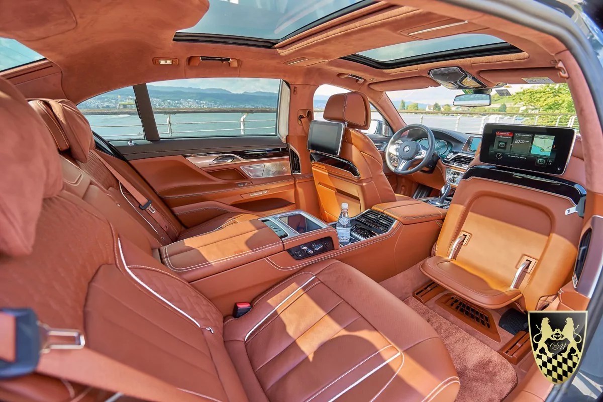 Luxurious car interior with brown leather seats and panoramic sunroof.