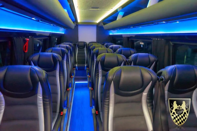 Interior of a modern coach bus with blue lighting and empty black seats.
