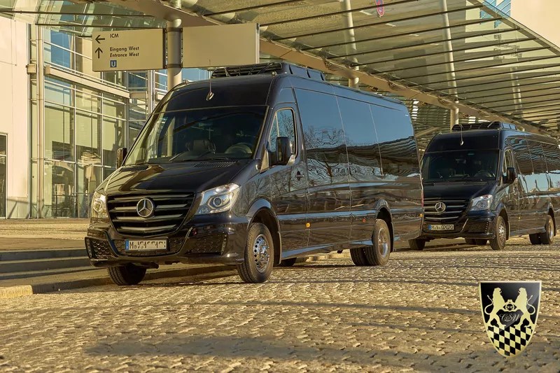 Two black Mercedes-Benz vans parked on a sunny street.