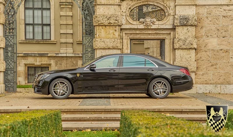 Black luxury sedan parked in front of ornate building entrance.