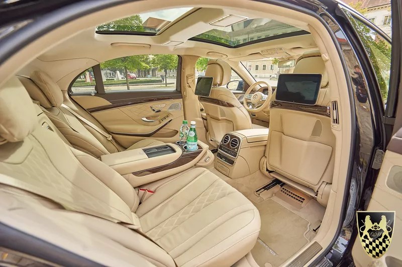 Luxurious car interior with beige leather seats and rear seat screens.