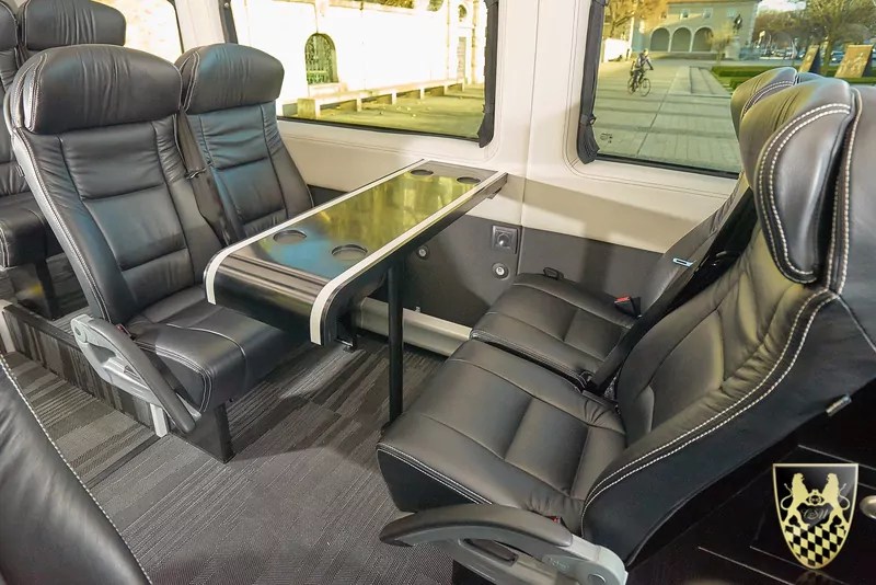 Luxury van interior with leather seats and center table.