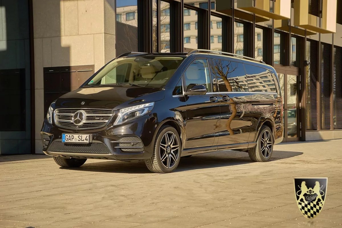Black Mercedes-Benz van parked on urban street with emblem on corner.