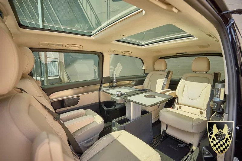 Luxury van interior with beige leather seats and a retractable table.