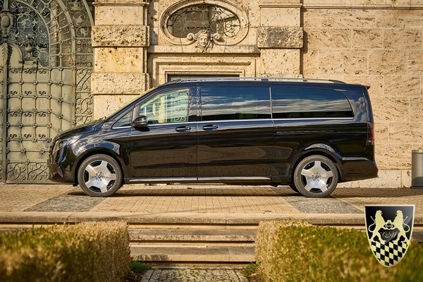 Black van parked in front of an ornate stone building.