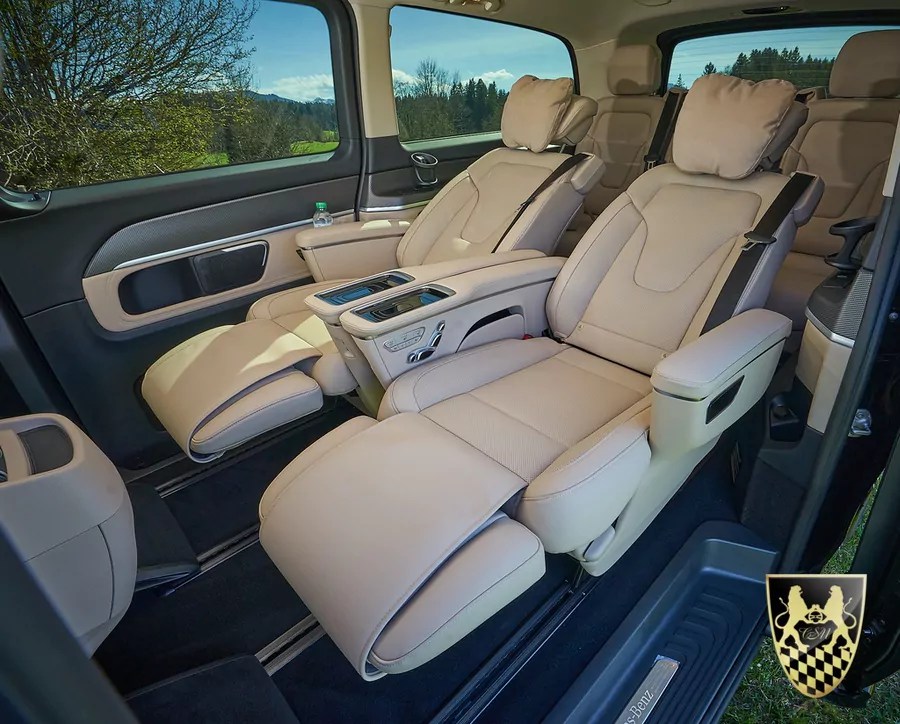 Luxury car interior with beige reclining seats and a panoramic window view.
