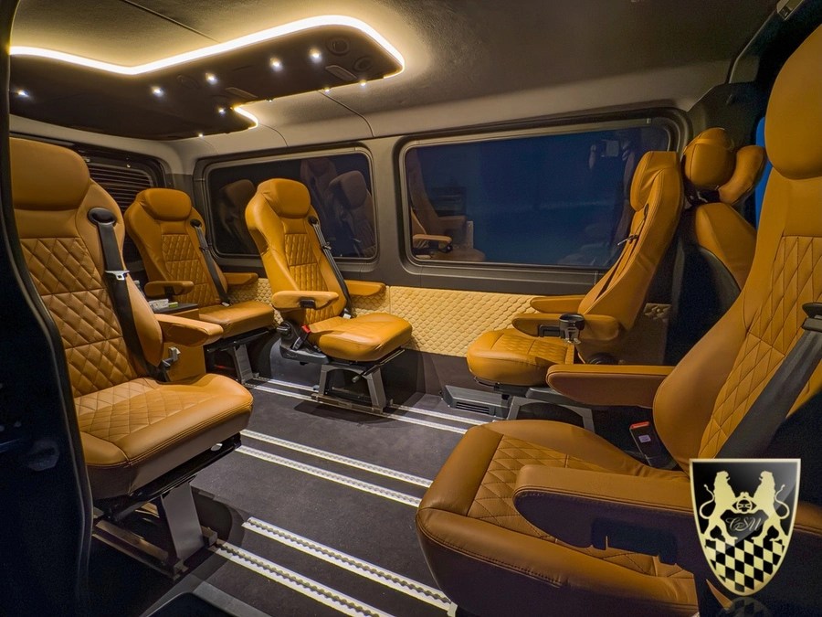 Luxury van interior with brown leather seats and ambient lighting.