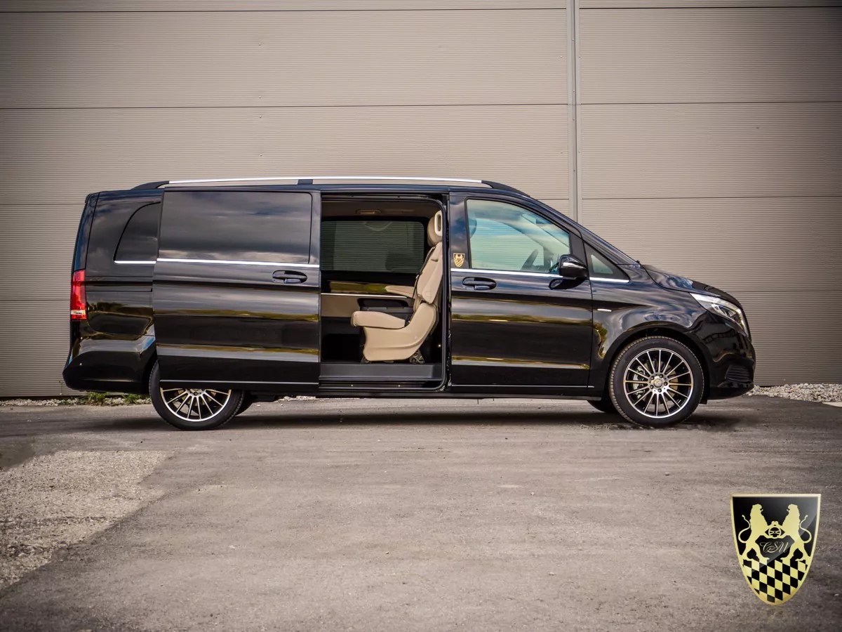 Black van with sliding door open, showing tan interior next to a gray wall.