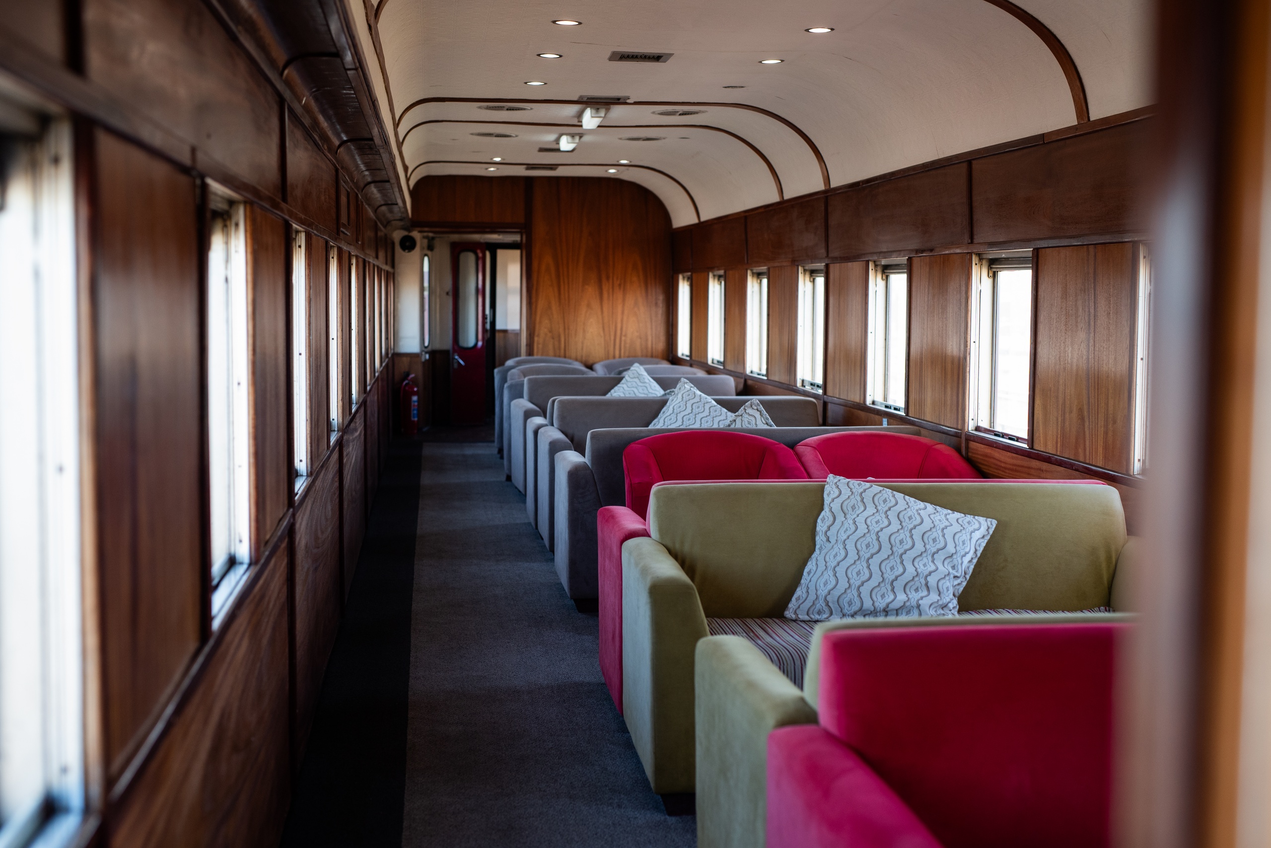 Interior of a vintage train with colorful seats and wooden walls.