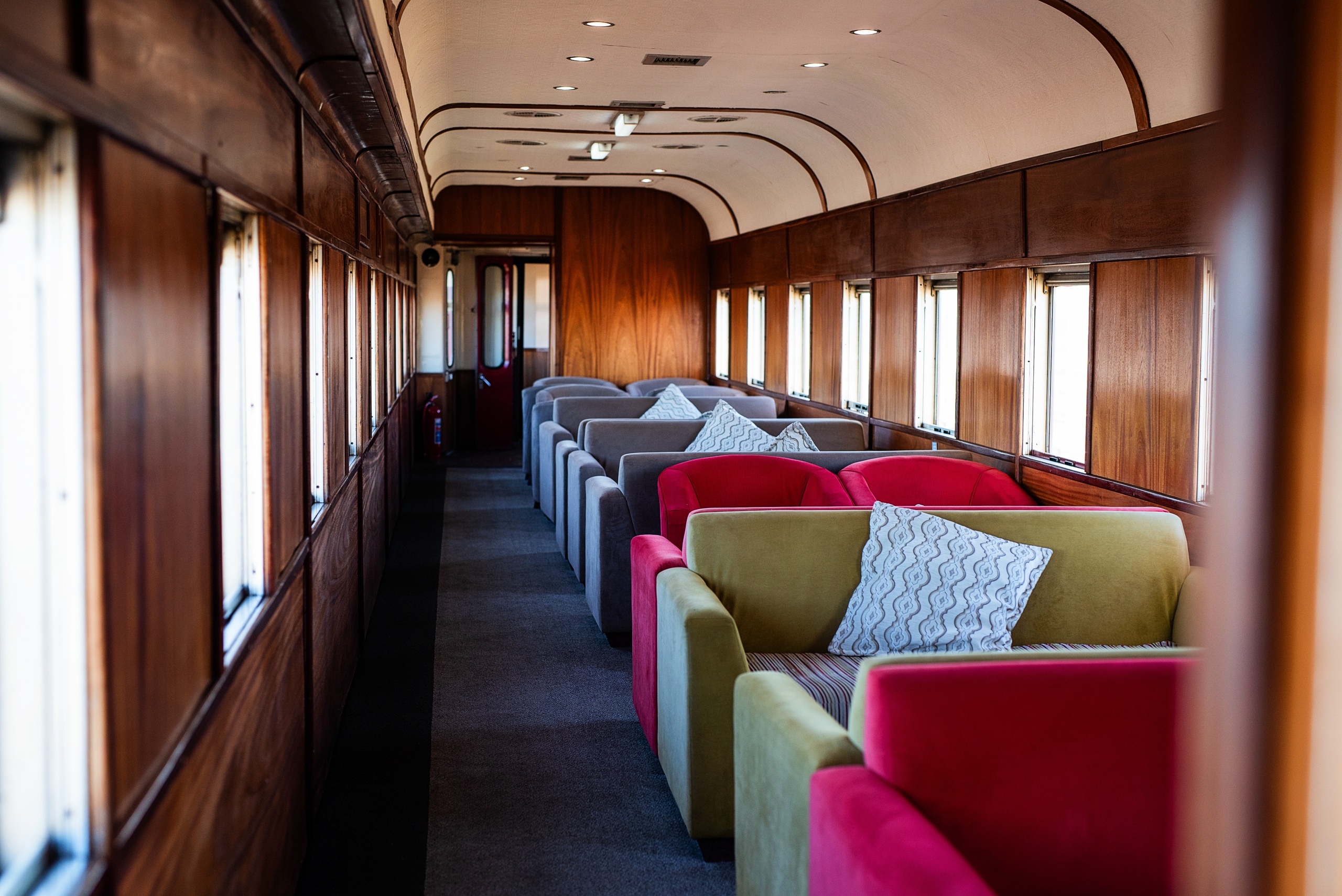 Vintage train interior with colorful sofas and wooden walls.