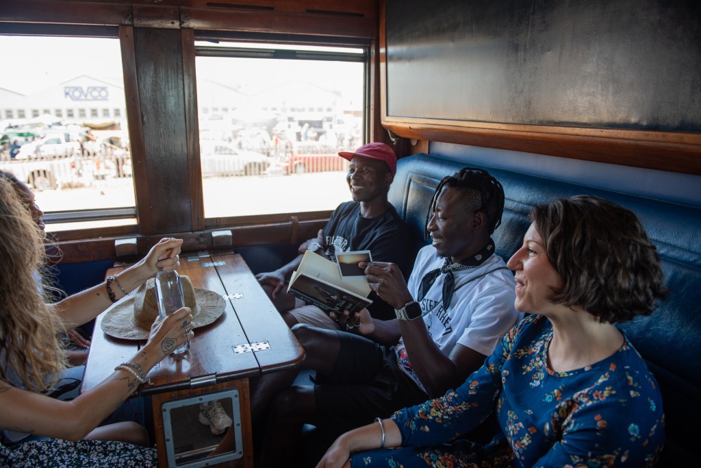 Group of four people talking and laughing in a train cabin.