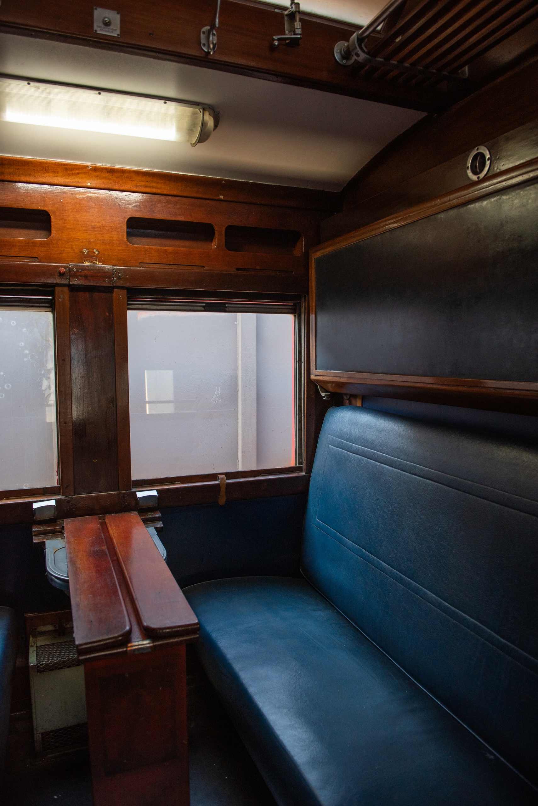Vintage train compartment with wooden interior and blue leather seats.