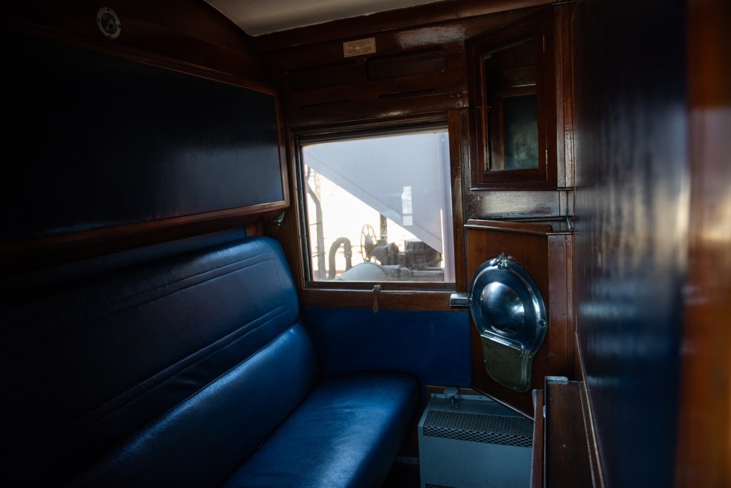Vintage train cabin with blue seats and a window view.