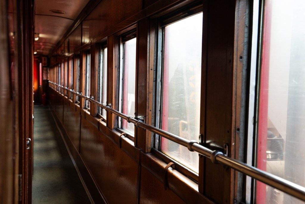 Narrow train corridor with windows on the right side.