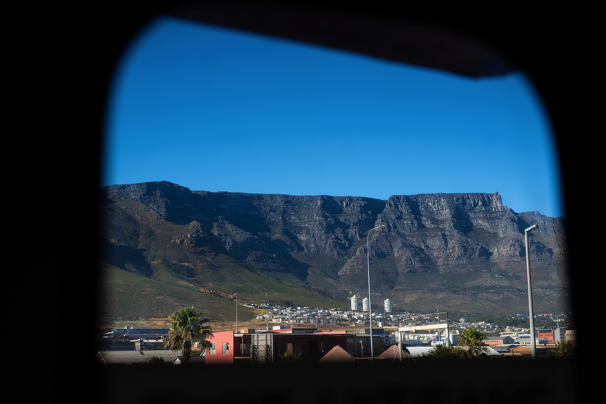 Mountain view framed by a window with a clear blue sky.
