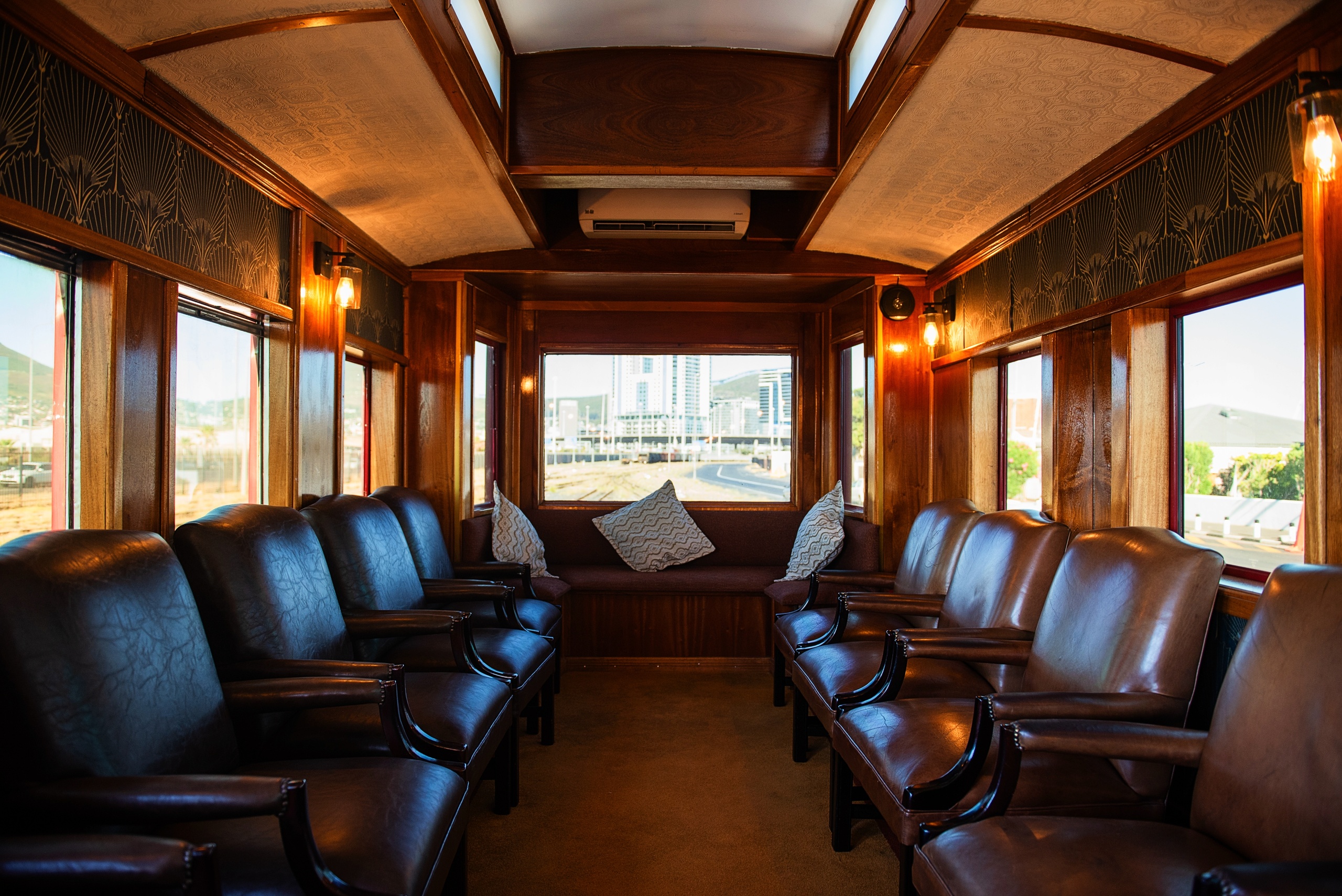 Interior of vintage train carriage with leather seats and wooden paneling.