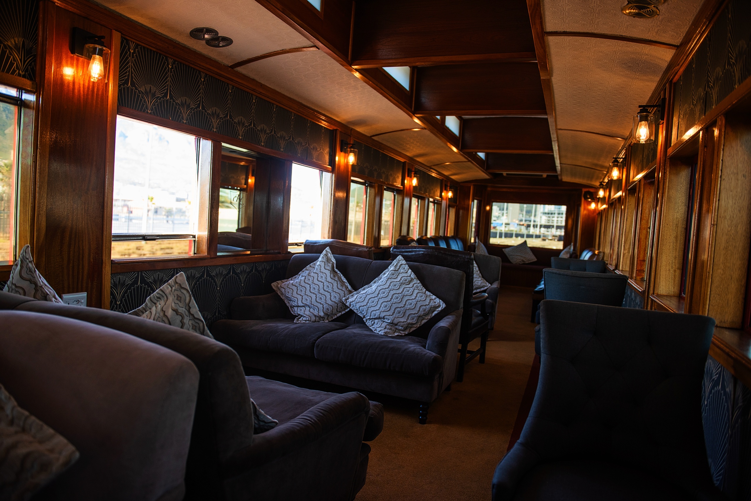 Luxurious train carriage with plush sofas and large windows.
