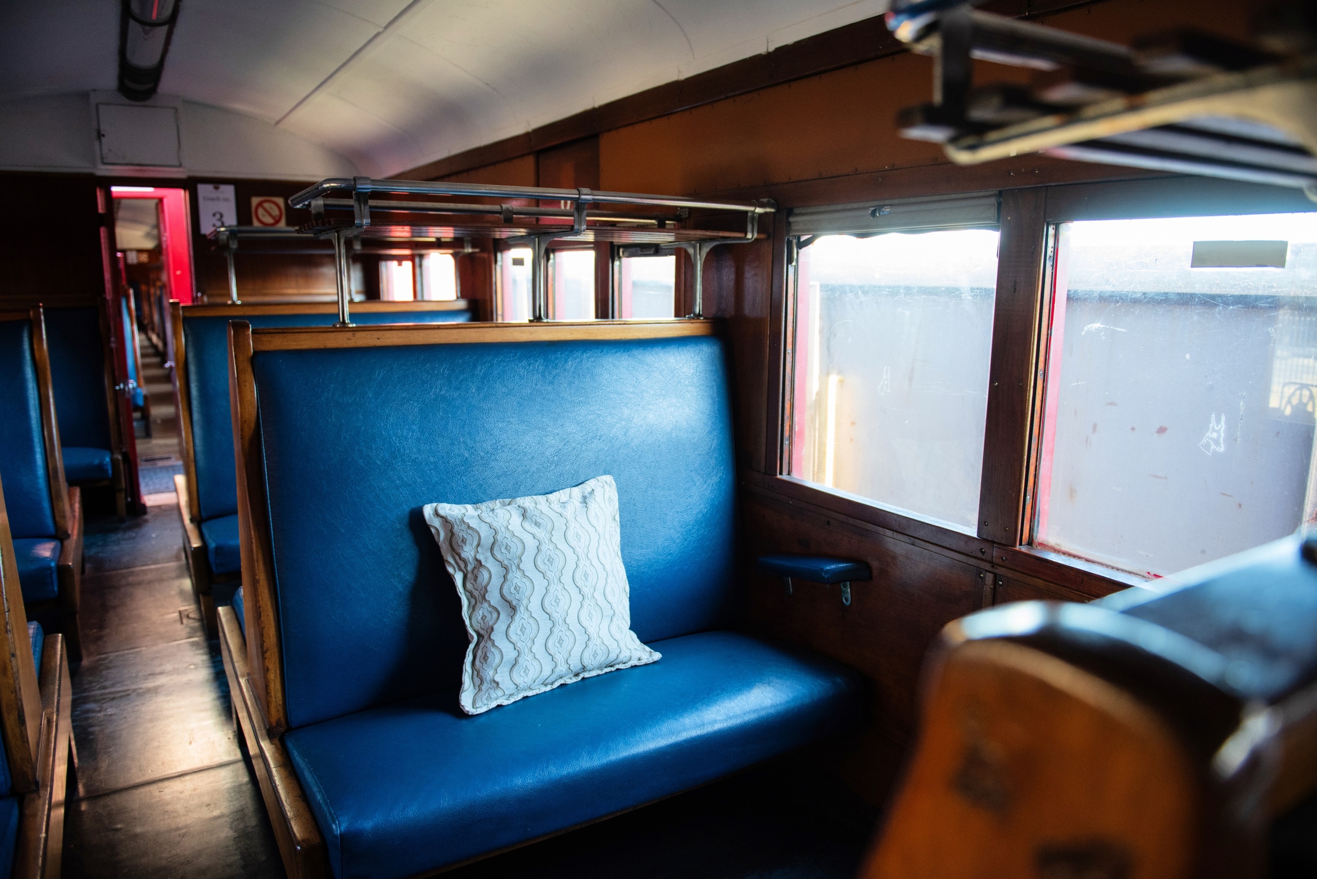 Empty vintage train carriage with blue seat and pillow.