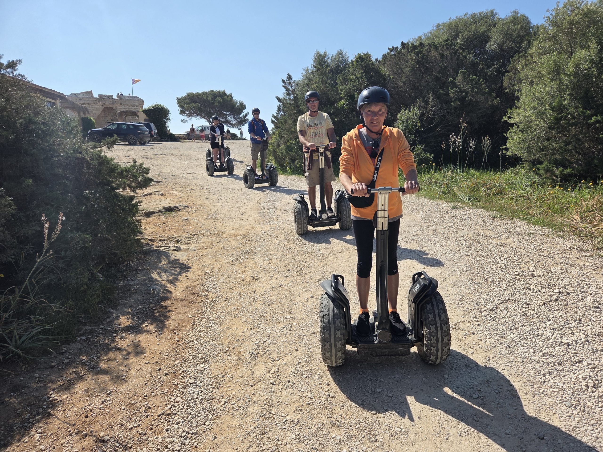 People riding Segways on a gravel path with trees in the background.