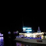 Boats decorated with festive lights on a dark waterway at night.