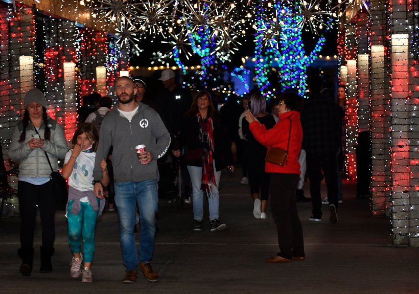 People walking under festive lights in a decorated outdoor area at night.